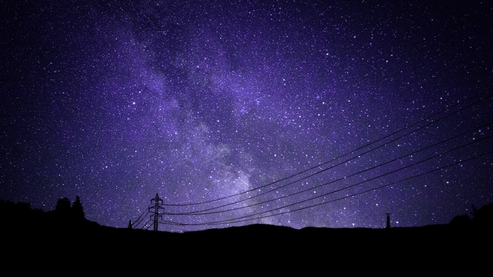 Milky Way galaxy over a silhouetted landscape with power lines