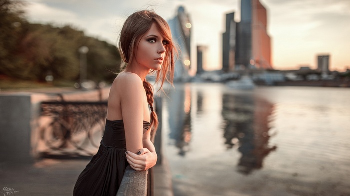 Woman in black dress by the river with city skyline