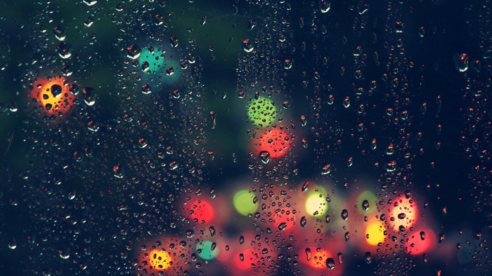 Raindrops on glass with blurred colorful lights