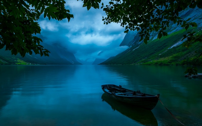 Boat on a lake in Norway with mountains and clouds
