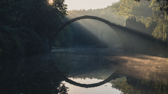 Rakotzbrücke bridge over a lake with sun rays