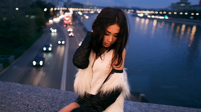 Asian woman sitting by a river at night