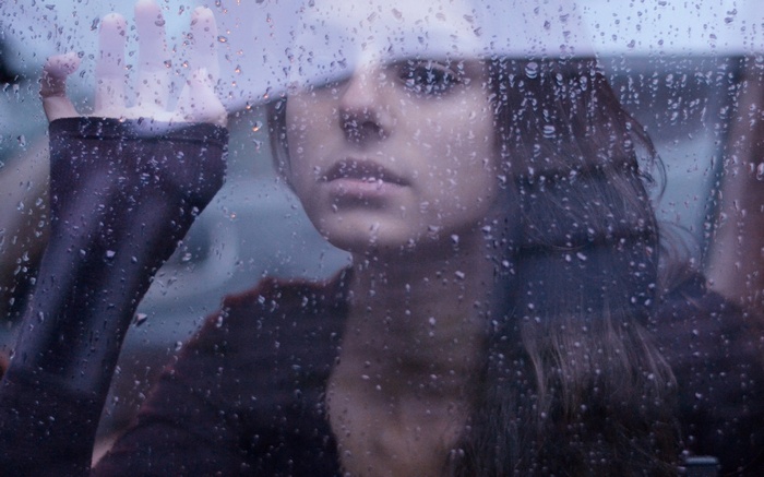 Woman looking through a rain-covered window