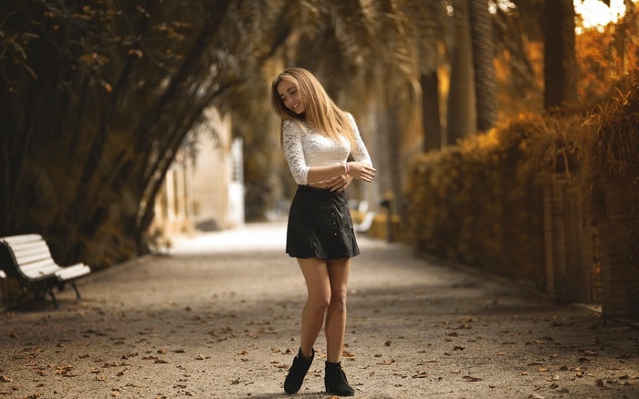 Woman with long blonde hair in a white top and black skirt