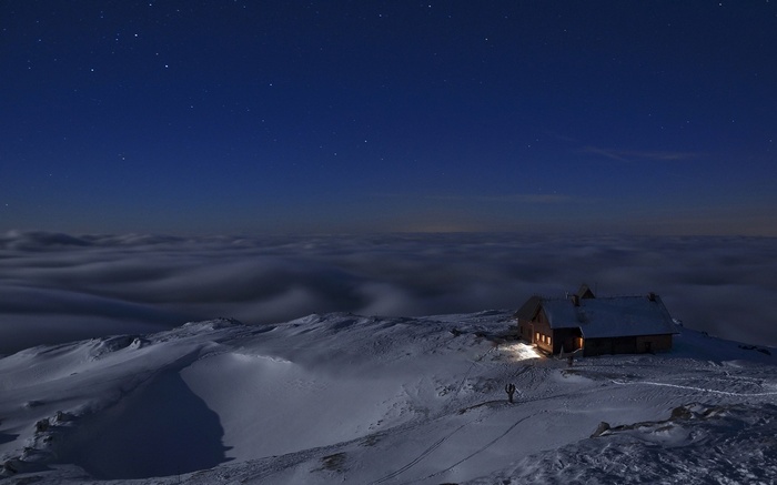 Snowy mountain cottage under a starry night sky