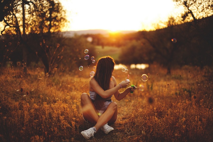 Woman blowing bubbles at sunset