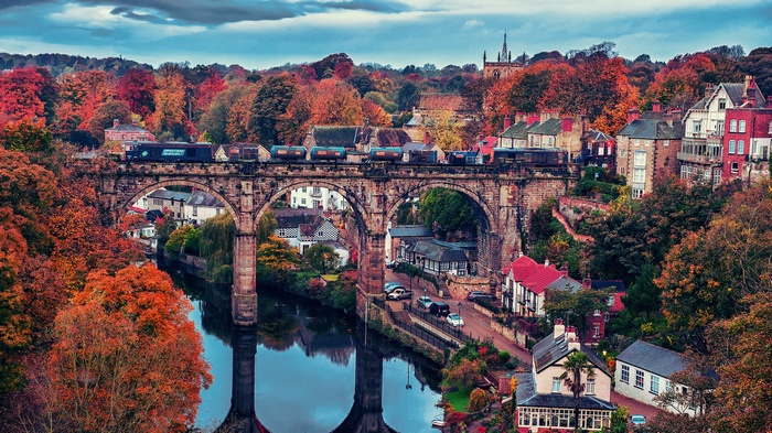 Train crossing a stone viaduct in Knaresborough during autumn