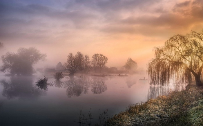 Misty river landscape with a fisherman in a boat