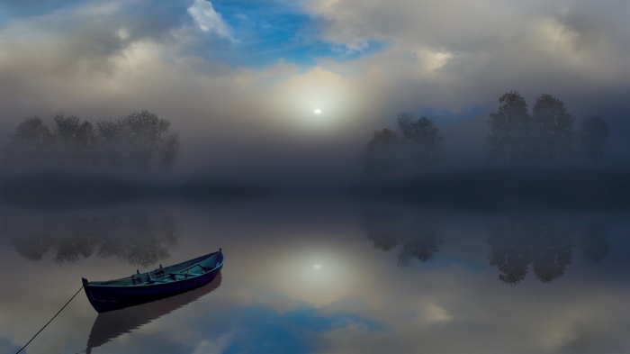 Boat on a misty lake with trees and clouds