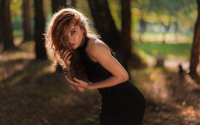Woman with auburn hair in a black dress outdoors