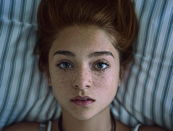 Young redhead woman with freckles lying down