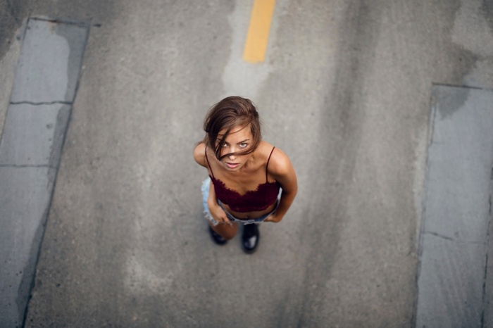 Woman in burgundy lace top and denim shorts looking up