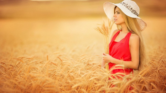 Woman in red dress and hat in a wheat field