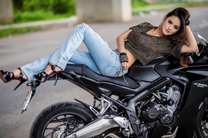 Asian woman in jeans and high heels on a Honda CBR motorcycle
