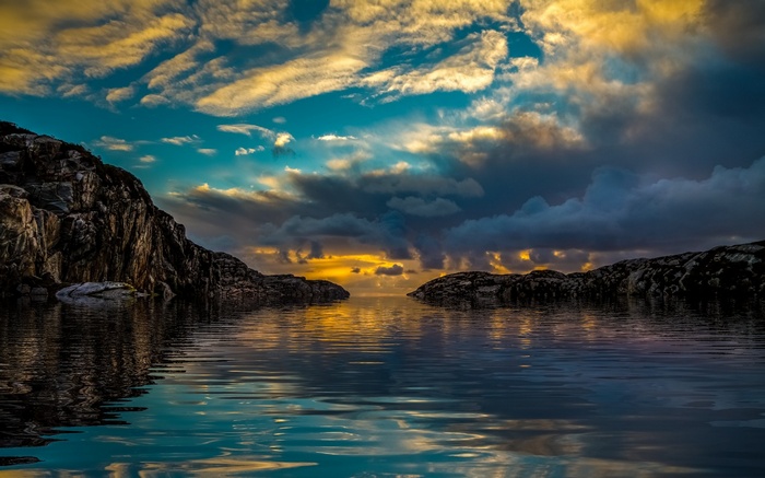 Sunset over the ocean with rocky coastlines and reflection