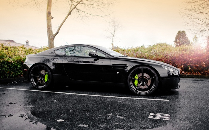Black Aston Martin Vantage parked on wet asphalt