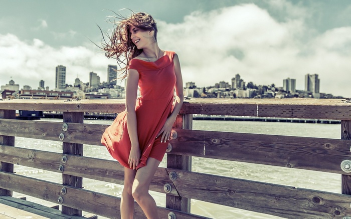 Woman in red dress on a pier with cityscape background