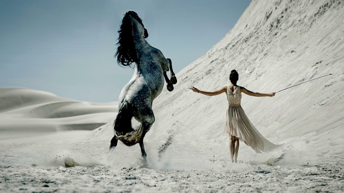 Woman with a rearing horse in a desert
