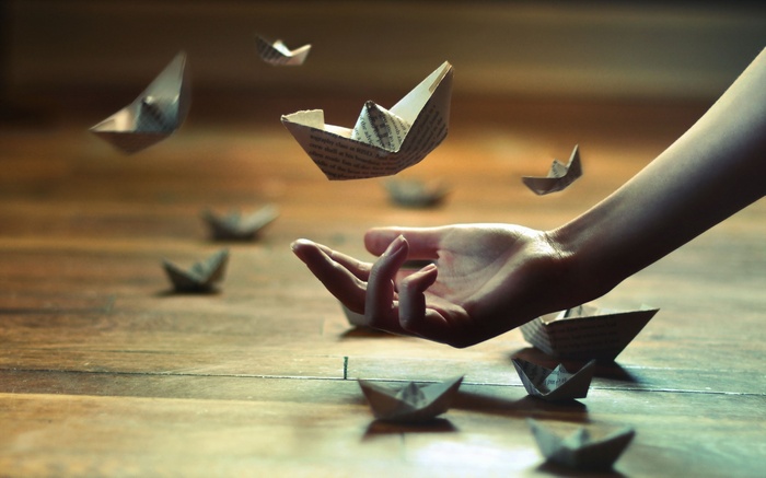 Paper boats floating around a hand