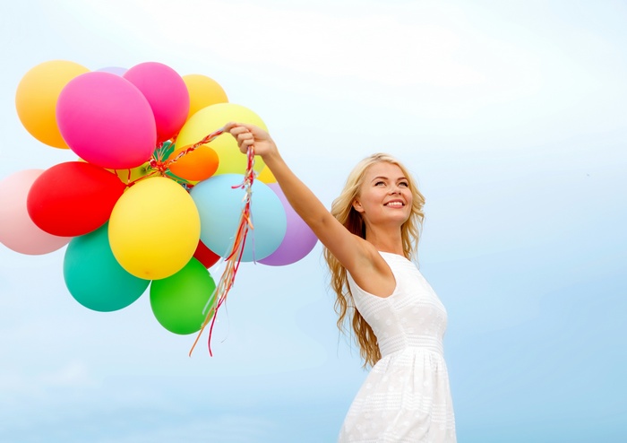 Woman holding a bunch of colorful balloons
