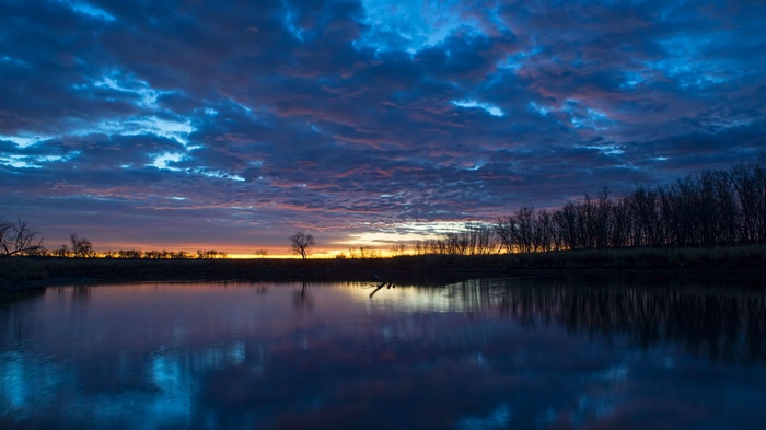 Sunset over a calm lake with dramatic clouds