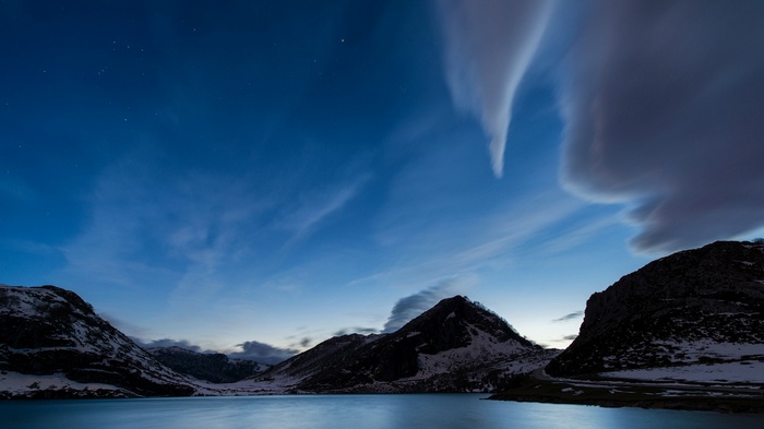 Mountain lake landscape at night with stars and clouds