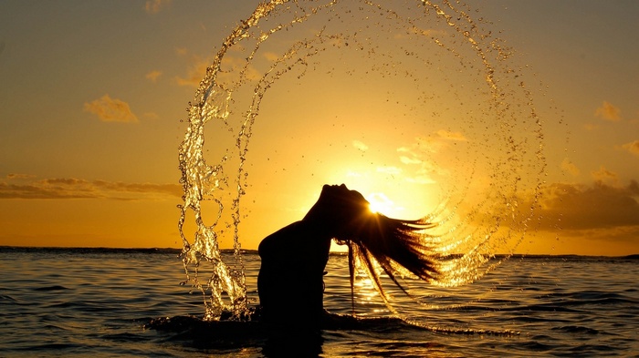 Woman splashing water at sunset