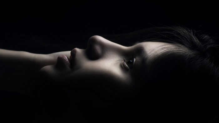 Woman's face in profile with dark hair and background