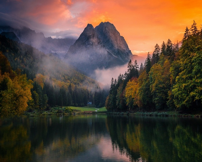 Mountain lake at sunset with autumn forest and mist