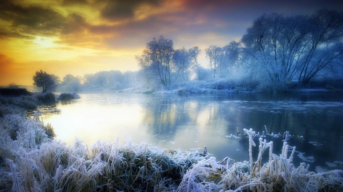 Winter landscape with frosted trees and a river at sunrise