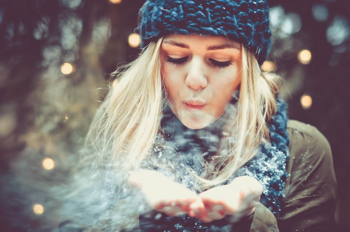 Woman in a blue hat blowing snow