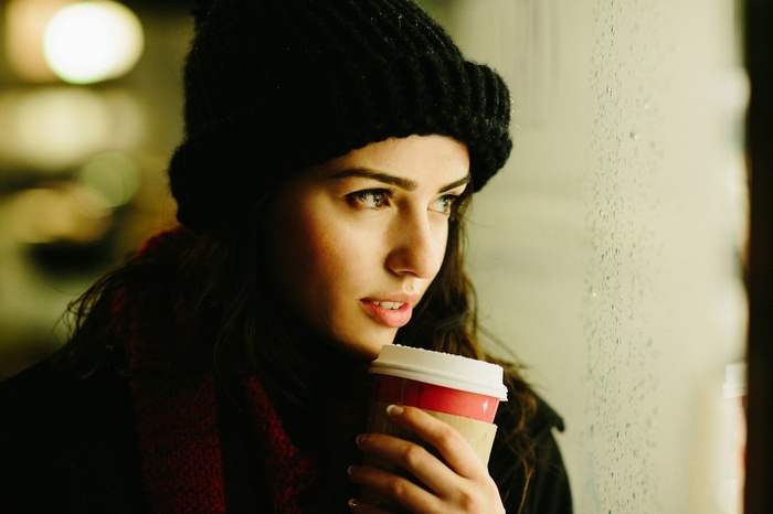 Woman in a woolly hat holding a cup