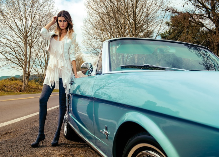 Woman in white dress and jacket with blue convertible car