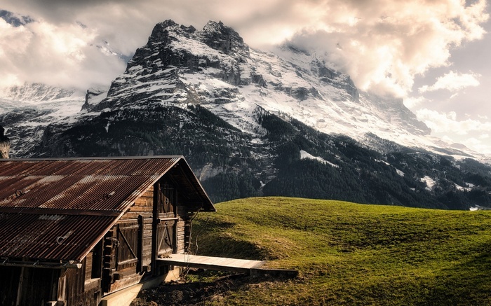 Wooden cabin in front of a snowy mountain peak in Switzerland