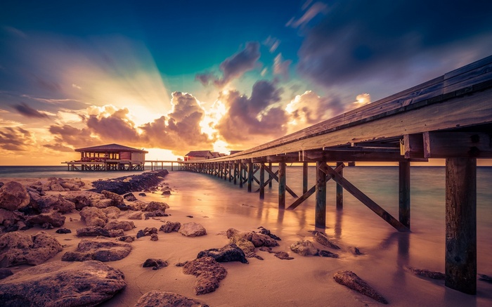 Maldives resort pier at sunset with sun rays