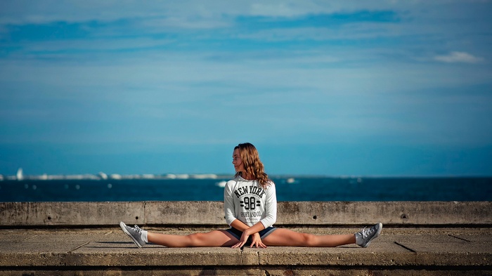 Woman doing splits by the ocean