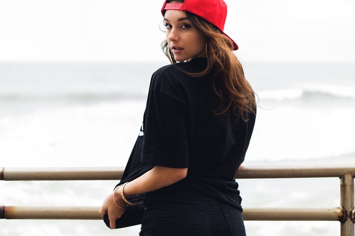 Woman in red baseball cap and black t-shirt looking back