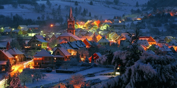 Snowy village in France with illuminated houses and church
