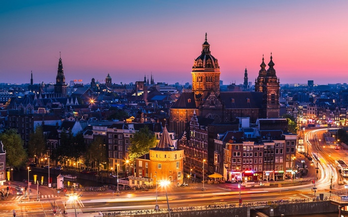 Amsterdam cityscape at sunset with illuminated buildings and roads