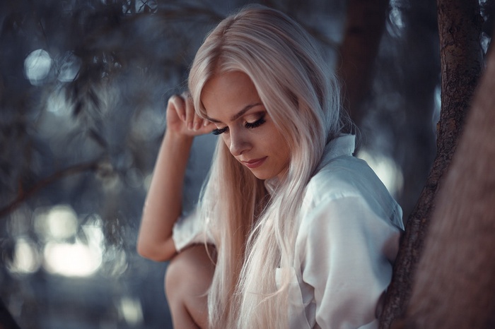 Blonde woman with closed eyes sitting in a tree