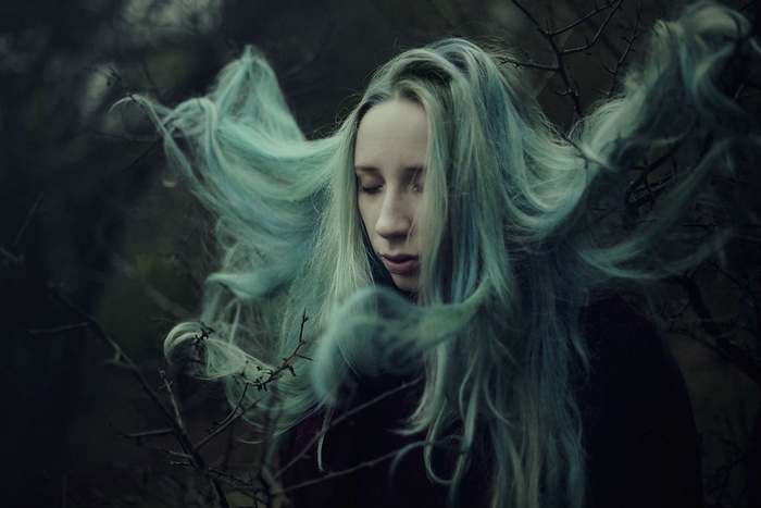 Woman with flowing blue hair in a dark forest