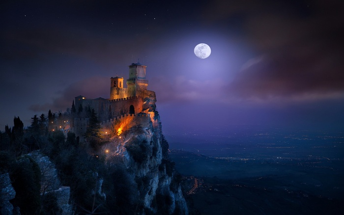 Castle on a cliff under a full moon at night