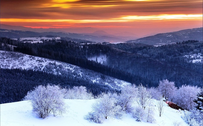 Snowy mountain valley at sunset with colorful sky