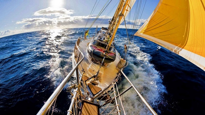 Sailboat sailing on the ocean with yellow sail