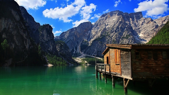 Wooden cabin on a turquoise lake with mountains