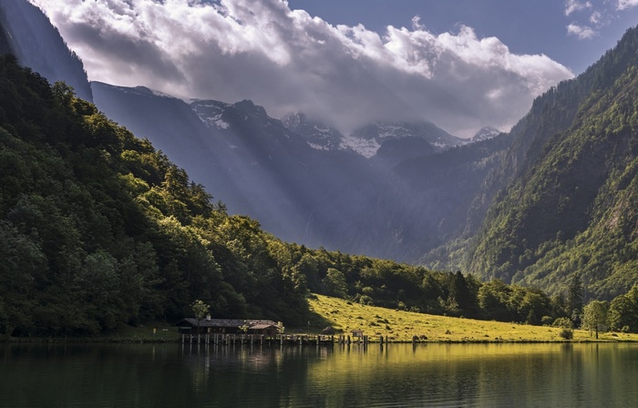 Lake and mountains with sun rays and a house
