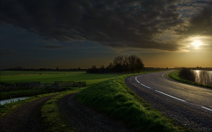 Road curving through a Dutch landscape with windmills at sunset