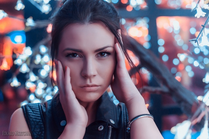 Woman with hands on her face in front of bokeh lights