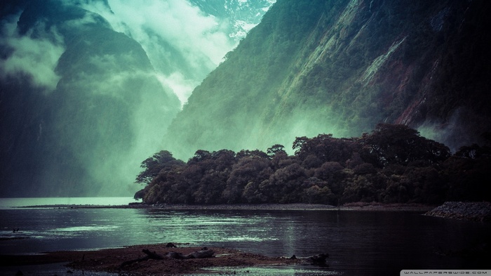 Misty mountains overlooking a dark forest and lake