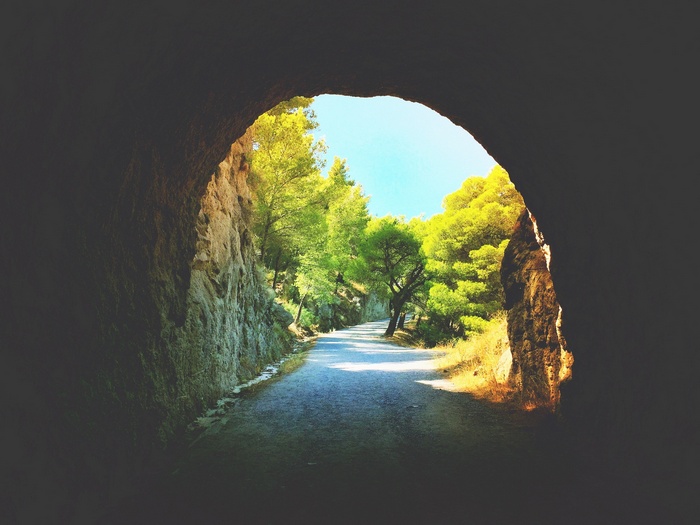 Path through a rock tunnel surrounded by trees